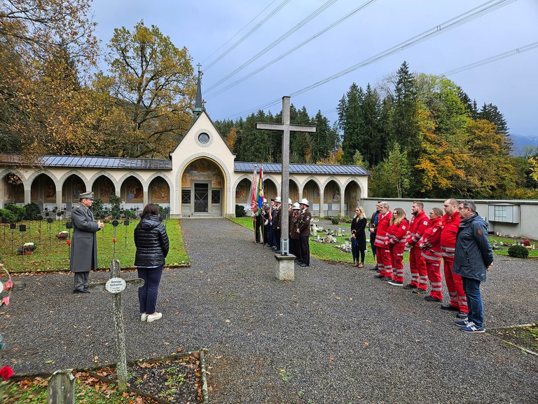Bürgermeisterin Katharina Wöß-Krall und Oberst Erwin Fitz, Landesgeschäftsführer des Österreichischen Schwarzen Kreuzes, sowie Vertreter*innen des Roten Kreuzes auf dem Soldatenfriedhof beim Landeskrankenhaus Rankweil (© Marktgemeinde Rankweil)