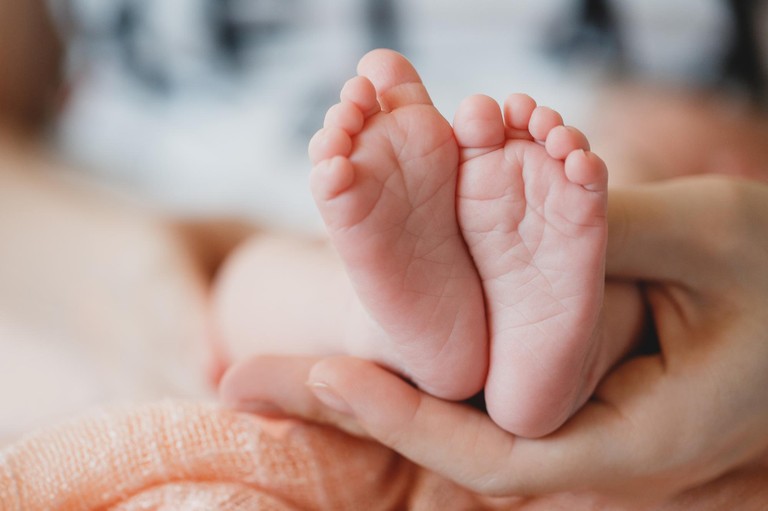 Beispielbild: Kinderfüße in Händen eines Erwachsenen © freepik